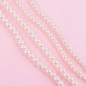 Detail shot of white pearl strands for cake decoration on a soft pink background.