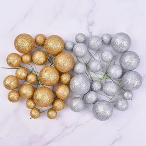 Assorted sizes of gold and silver glitter ball cake toppers displayed on a marble surface