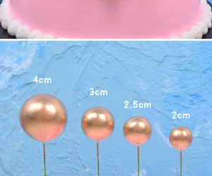 Detailed macro view showing four sizes of golden metallic sphere cake toppers from 2cm to 4cm