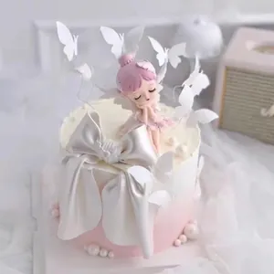 Detailed view of dreamy pink fairy figurine and elegant white butterfly cake topper decorations