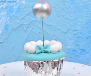 Detail shot of a silver metallic ball cake topper with a light blue bow on a cupcake
