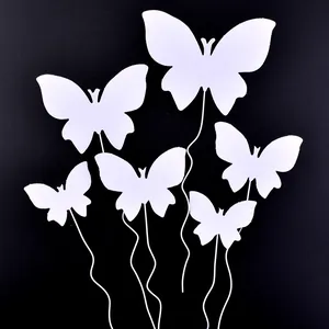 Detailed view of six white butterfly cake toppers on wavy sticks against a black backdrop