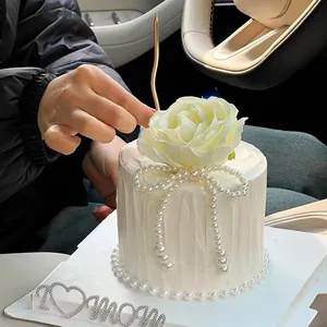 Close-up of elegant pearl and rose cake decorations with I love mom topper in a car scene.