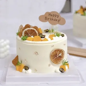 Close-up of kraft paper cloud-shaped 'Happy Birthday' cake topper on fruit cake