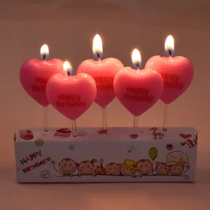 Close-up of five pink heart-shaped lit candles with Happy Birthday embossed text.