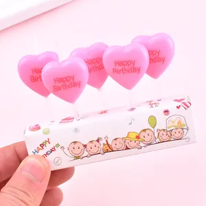 Close-up detail of pink heart-shaped birthday candles with Happy Birthday message for cake decor