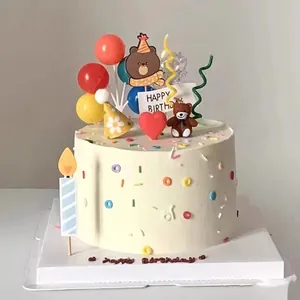 Close-up detail of retro mini party hats and cute bear cake toppers on a cream cake