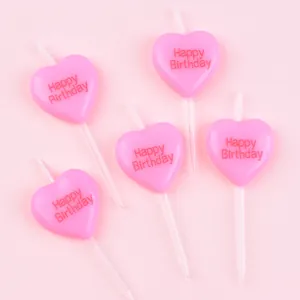 Close-up view of five pink heart-shaped birthday candles with Happy Birthday embossing