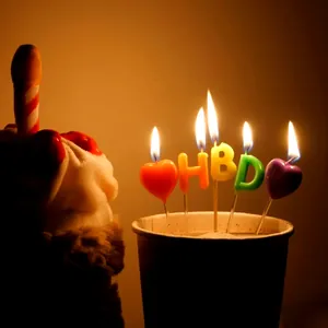 Dettaglio di candele di compleanno a forma di cuore e HBD con candela a forma di dito.