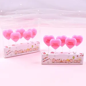Detailed shot of pink heart-shaped birthday candles featuring Happy Birthday engraving.
