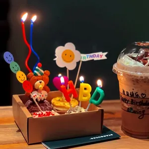 Primo piano di candele colorate HBD e decorazione a orsetto su un dolce di compleanno