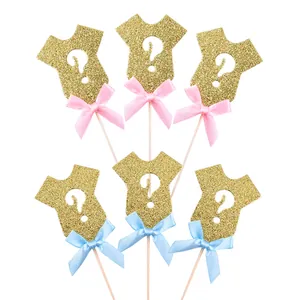 Detail of glitter onesie cake toppers with pink and blue bows for gender reveal.