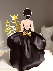 Detail of elegant woman back cake topper with black satin dress and gold bow for baking.