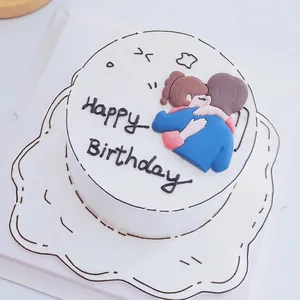 Close-up of a cute hugging couple cake topper made of soft glue with Happy Birthday text.