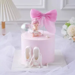 Detailed view of pink mesh bow topper and ballerina figurine on a birthday cake