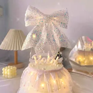 Close-up view of a glitter bow cake topper and Baby LED light on a decorated cake