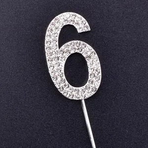 Detailed view of a silver rhinestone-encrusted number 6 cake topper for birthday decor.