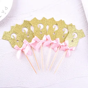 Detail of gold glitter onesie cupcake toppers with pink bows for gender reveal party