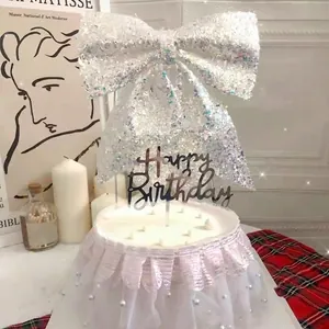 Close-up of elegant iridescent glitter bow cake topper and white lace pearl cake skirt.