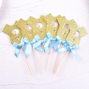 Detailed view of 6 glittery gold onesie-shaped cake toppers with blue bows.