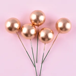 Detailopname van vijf roségouden metallic schuimbal taartdecoraties op een roze ondergrond