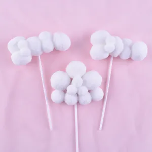 Detailed view of fluffy white pom-pom cloud cake toppers placed on a pink background