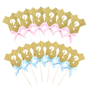 Gender reveal cake toppers featuring gold glitter baby onesies with pink and blue ribbons