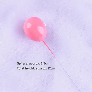 Close-up detail showing the glossy pink finish and wire stem of the balloon cake topper.