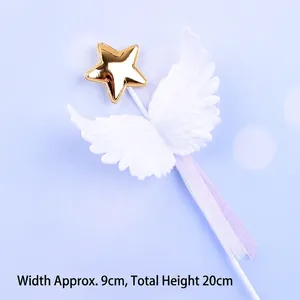 Detailed close-up of a white angel wings cake topper with a gold star and purple ribbon.