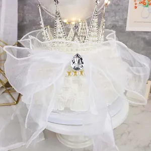 Close-up detail of a dreamy silver pearl crown and white organza ribbon cake topper set