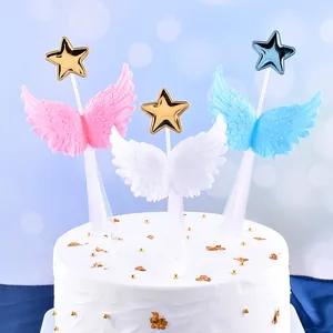 Detailed view of 3D angel wing cake toppers with stars on a white frosted cake