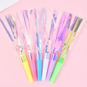 Colorful iridescent party blowouts with foil streamers on pink background closeup