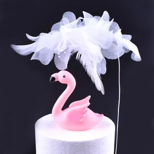 Detail eines rosa Flamingo-Kuchensteckers mit weißer Netzblüte und Federakzenten