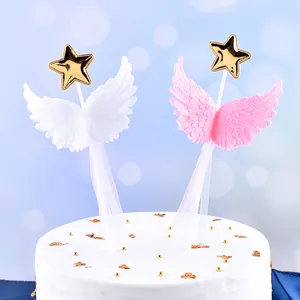 Detail of 3D angel wing cake toppers with gold stars on a festive white cake