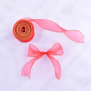 Vista dettagliata del fiocco e del rotolo di nastro in organza rosa con bordi dorati.