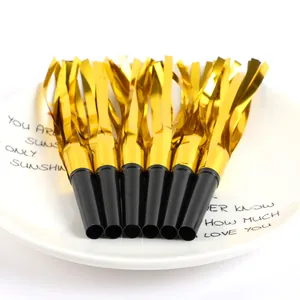 Six golden foil party blowouts whistles on a white decorative plate detail view