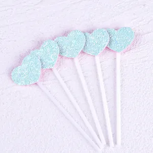Detailed close-up of five light blue glitter heart cake toppers on white plastic sticks
