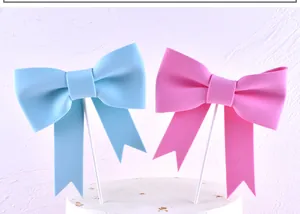 Pink and blue bowtie cake toppers inserted in a white cake for birthday parties