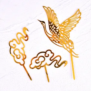 Close-up view of a 3-piece golden acrylic set featuring a crane and cloud cake toppers.