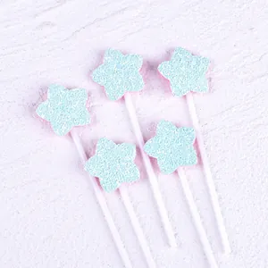 Close-up of five-pointed star cake toppers with light blue glitter fabric texture