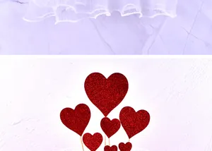 Macro view of red glitter heart cake toppers with white mesh tulle fabric details.