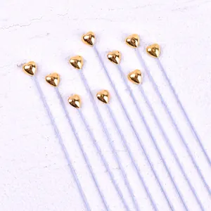 Nahaufnahme von goldenen herzförmigen Tortenaufsätzen mit langen weißen Stielen.