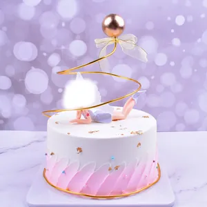 Detailed view of an elegant golden spiral cake topper with a rose gold ball and bow