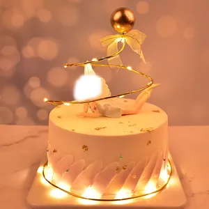 Close-up detail of elegant golden spiral cake topper with warm LED lights and decorative bow