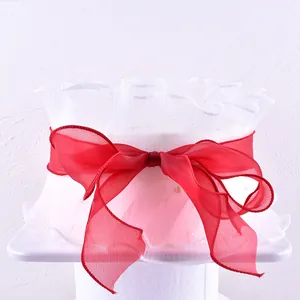Elegant white mesh cake collar with decorative red organza bow for birthdays.