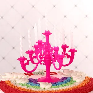 Close-up of mini magenta plastic candelabra with white candles on a cake