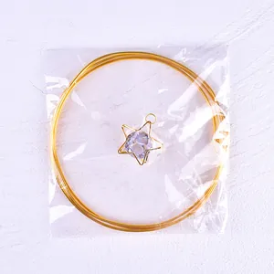 Close-up of gold iron wire circle and crystal star pendant cake topper in clear packaging