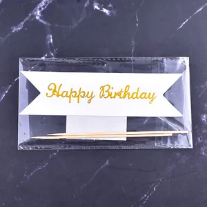 Détail d'une bannière de gâteau Happy Birthday dorée avec bâtonnets sous plastique