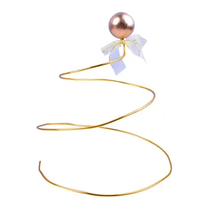 Elegant golden spiral iron cake topper with metallic ball and white ribbon bow