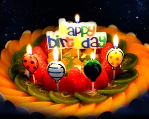 Lit Happy Birthday letter candle and decorative balloon-shaped candles on a fresh fruit cake
